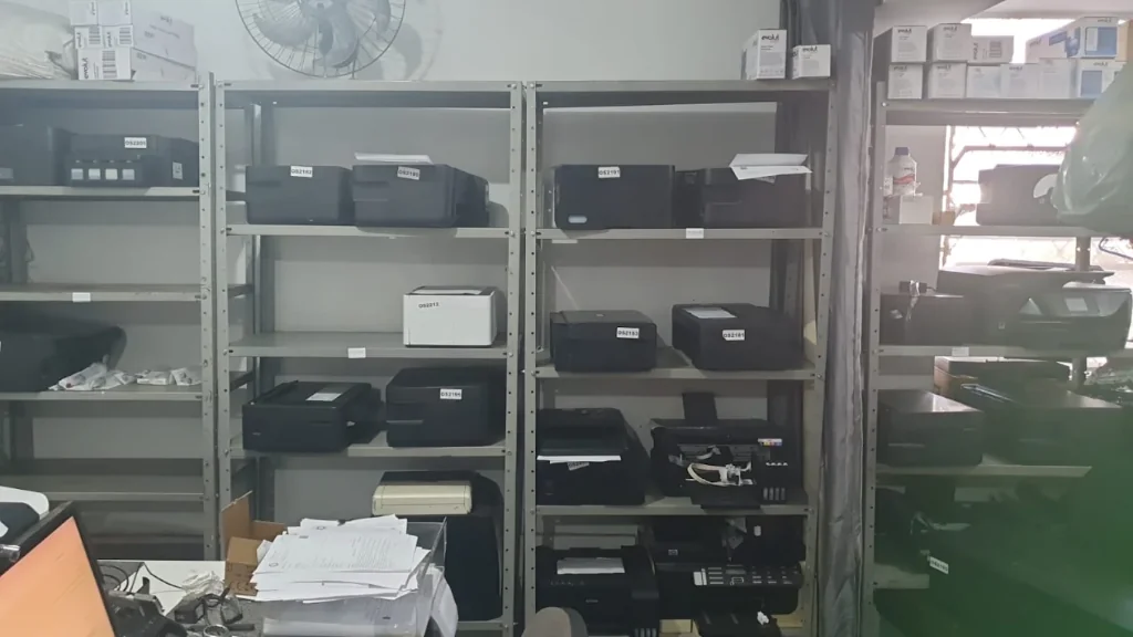 Prateleiras com impressoras e equipamentos na oficina da CTI em Belo Horizonte